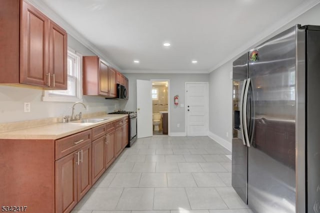 kitchen with baseboards, appliances with stainless steel finishes, light countertops, crown molding, and a sink