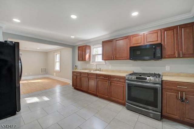 kitchen with light countertops, visible vents, a sink, black appliances, and baseboards