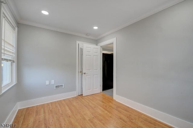 unfurnished room featuring light wood-style floors, baseboards, visible vents, and crown molding