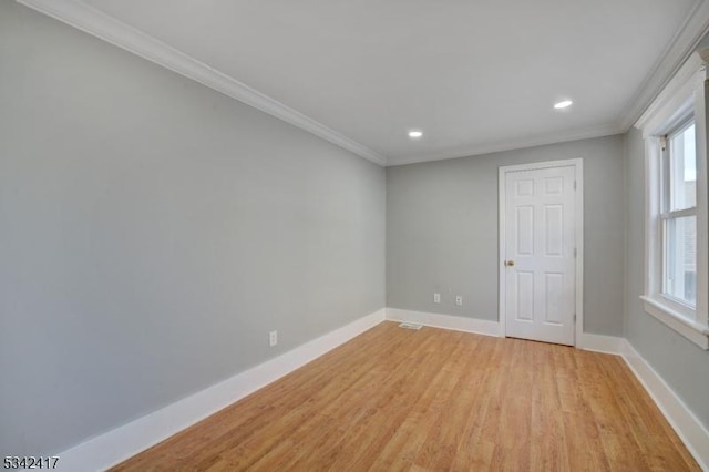 spare room featuring light wood-style floors, recessed lighting, crown molding, and baseboards