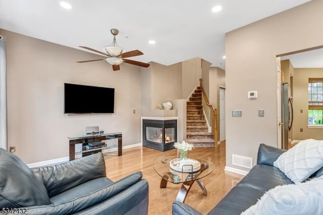 living room featuring recessed lighting, visible vents, stairway, wood finished floors, and a multi sided fireplace