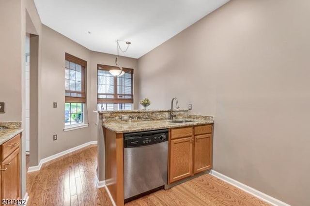 kitchen with light wood finished floors, brown cabinetry, a sink, dishwasher, and a peninsula