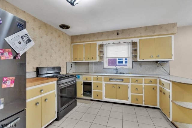 kitchen with open shelves, light countertops, appliances with stainless steel finishes, a sink, and wallpapered walls