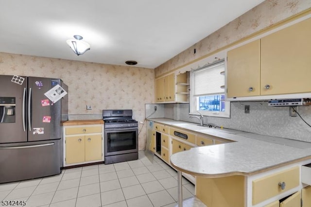 kitchen with open shelves, light countertops, appliances with stainless steel finishes, a peninsula, and wallpapered walls