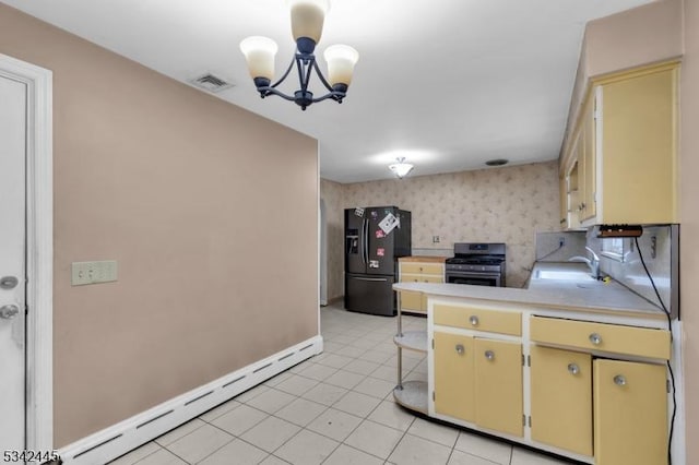 kitchen with stainless steel range with gas cooktop, visible vents, black refrigerator with ice dispenser, a baseboard heating unit, and wallpapered walls