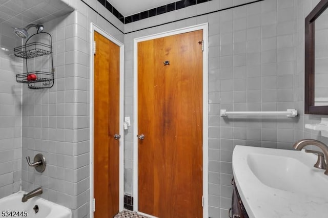 bathroom featuring washtub / shower combination, tile walls, and vanity