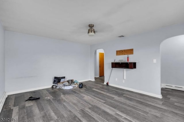 unfurnished room featuring baseboards, a baseboard radiator, arched walkways, and wood finished floors