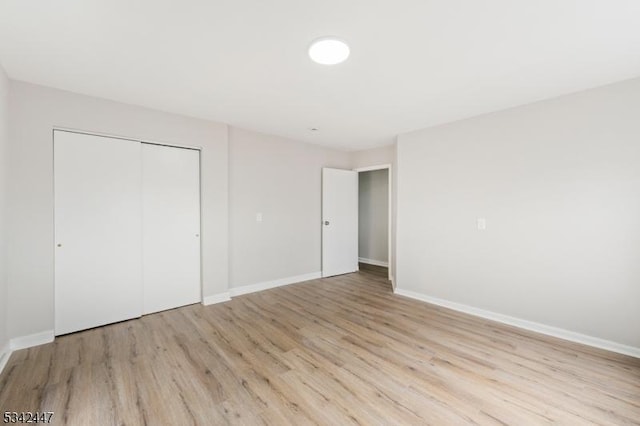 unfurnished bedroom with a closet, baseboards, and light wood finished floors