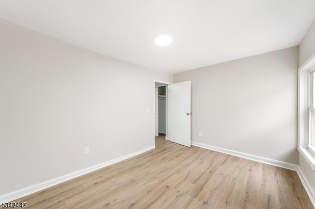 unfurnished room with light wood-style floors, baseboards, and a wealth of natural light