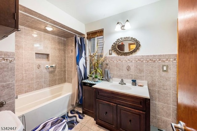 bathroom with shower / tub combo, wainscoting, tile patterned floors, vanity, and tile walls