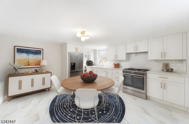 kitchen with marble finish floor, backsplash, stainless steel appliances, and a sink