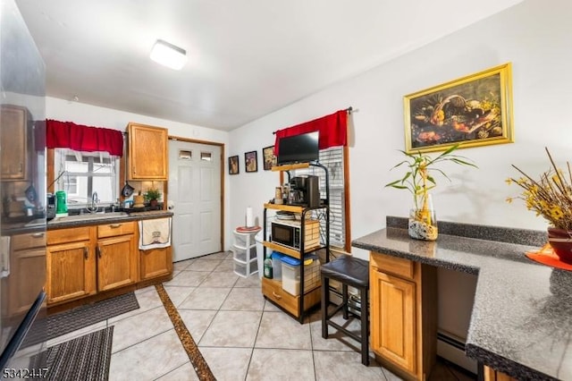 kitchen with dark countertops, brown cabinetry, a baseboard radiator, and a sink