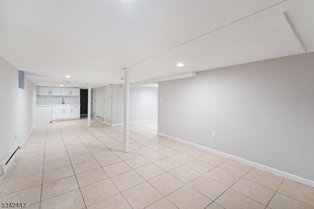 finished below grade area featuring baseboards, light tile patterned flooring, a baseboard radiator, and recessed lighting