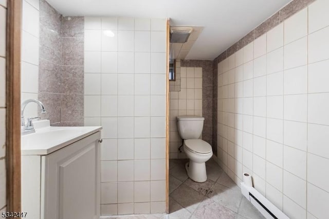 bathroom featuring toilet, vanity, tile walls, baseboard heating, and tile patterned floors