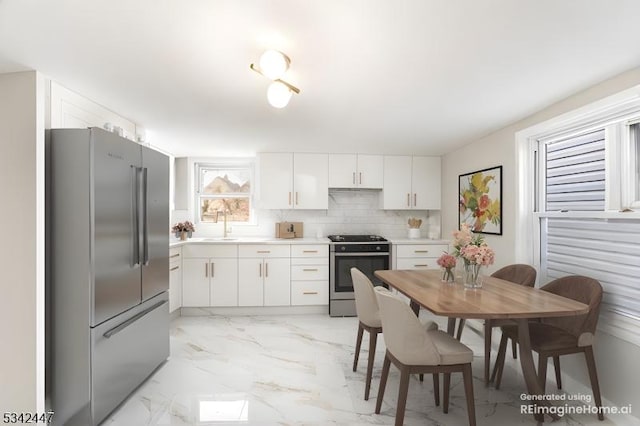 kitchen featuring marble finish floor, stainless steel appliances, tasteful backsplash, light countertops, and white cabinetry