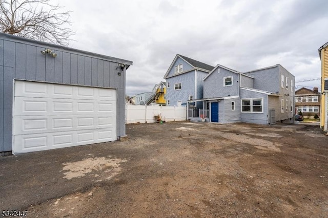 exterior space featuring a garage, an outbuilding, and fence