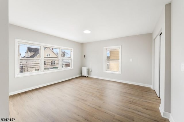 unfurnished bedroom featuring radiator, baseboards, and wood finished floors