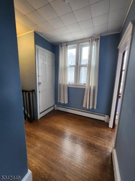 entrance foyer featuring a baseboard heating unit, a paneled ceiling, and wood finished floors