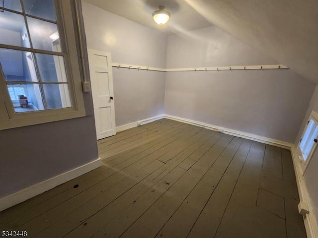 spare room featuring vaulted ceiling, dark wood-type flooring, and baseboards