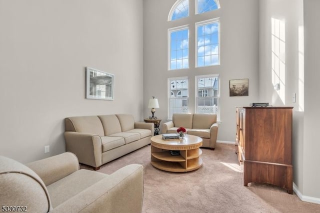 living room with light carpet, a high ceiling, and baseboards