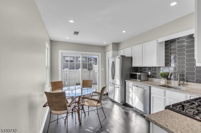 kitchen featuring stainless steel appliances, a sink, visible vents, and white cabinets