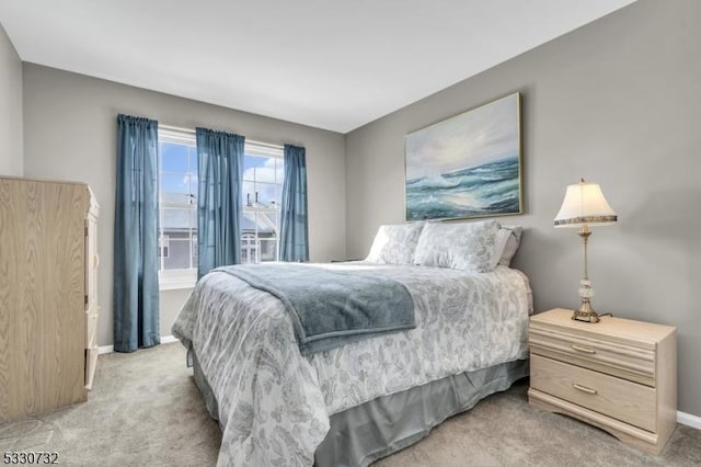 bedroom with baseboards and light colored carpet