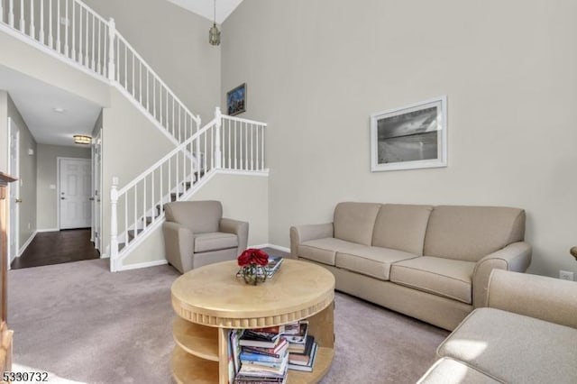 living area with stairs, carpet, a towering ceiling, and baseboards