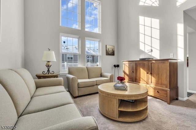 living room with light carpet, a towering ceiling, and baseboards