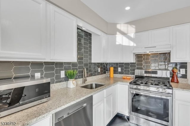 kitchen featuring under cabinet range hood, appliances with stainless steel finishes, white cabinets, and a sink