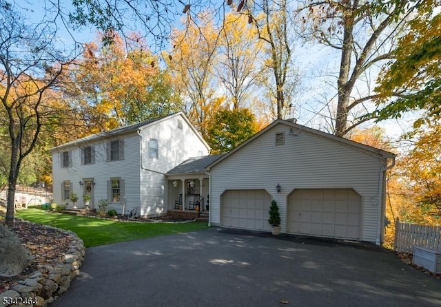 colonial house with aphalt driveway, a front yard, a garage, and fence