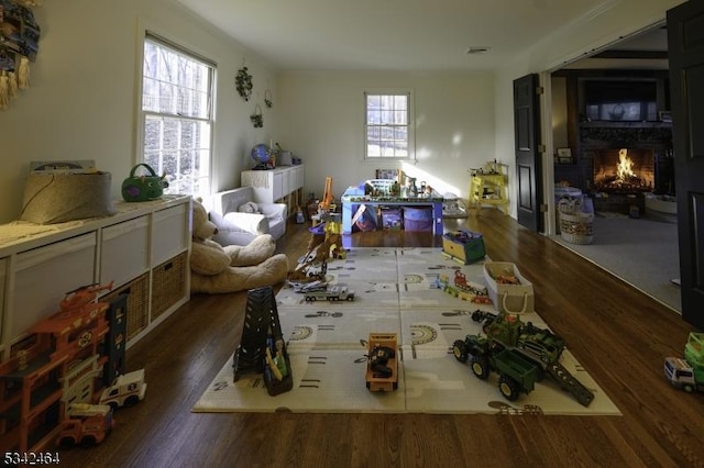 interior space with visible vents, a lit fireplace, and wood finished floors