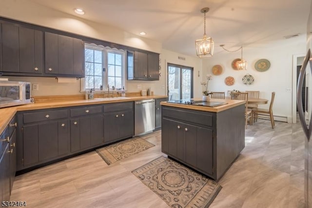 kitchen with a sink, light countertops, pendant lighting, stainless steel dishwasher, and a center island