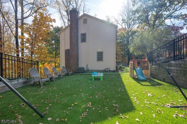 rear view of house featuring central air condition unit, a lawn, and a chimney