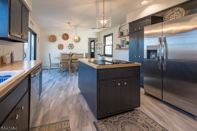 kitchen with pendant lighting, a baseboard heating unit, a kitchen island, light wood-style floors, and appliances with stainless steel finishes