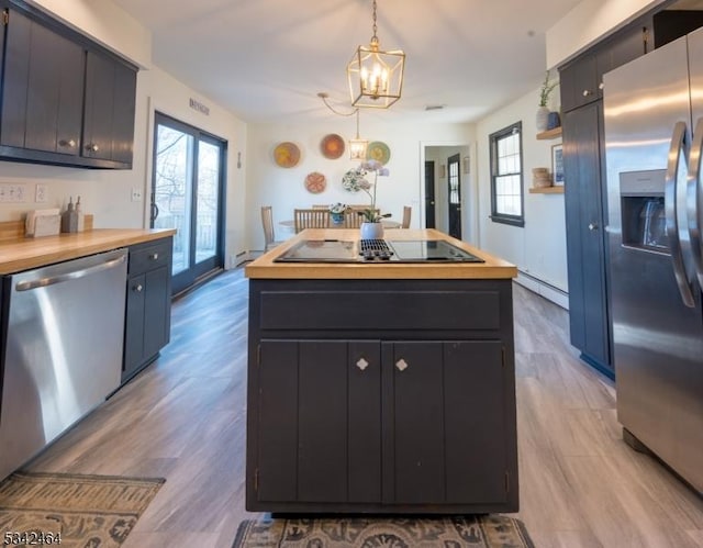 kitchen with decorative light fixtures, wood counters, a kitchen island, stainless steel appliances, and an inviting chandelier