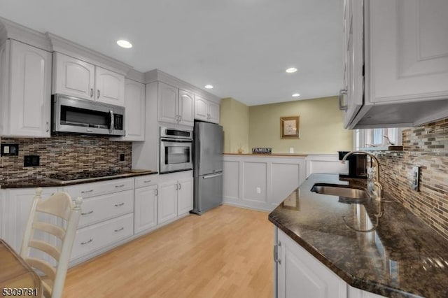 kitchen with white cabinetry, dark stone counters, appliances with stainless steel finishes, and a sink