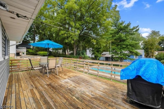 wooden terrace with outdoor dining space and grilling area