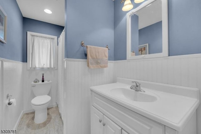 bathroom with vanity, toilet, and wainscoting