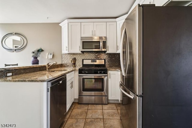 kitchen featuring a peninsula, a sink, white cabinetry, appliances with stainless steel finishes, and decorative backsplash