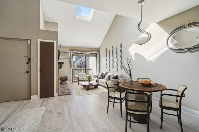 dining room featuring lofted ceiling with skylight, baseboards, and wood finished floors