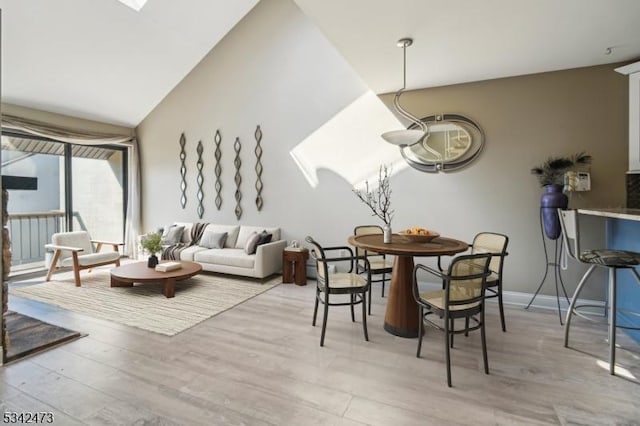 dining space with vaulted ceiling, light wood finished floors, baseboards, and a notable chandelier