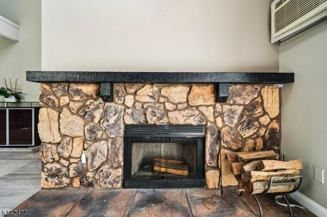 interior details featuring a stone fireplace, baseboards, and a wall mounted AC