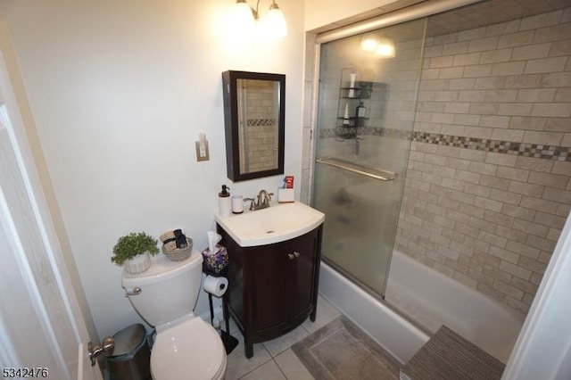 bathroom with combined bath / shower with glass door, vanity, toilet, and tile patterned floors