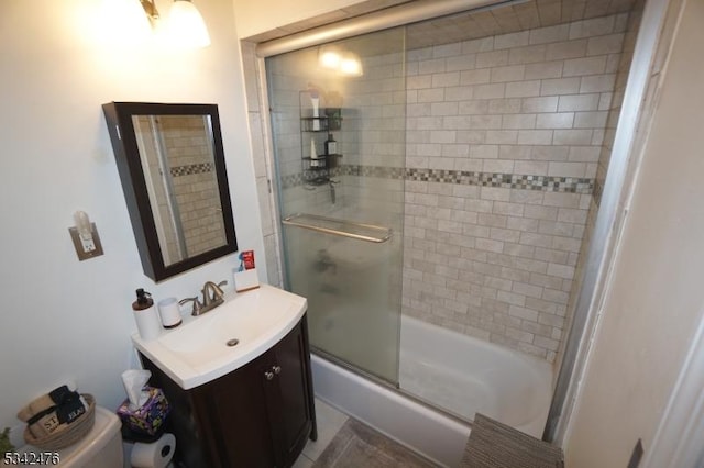 bathroom with toilet, combined bath / shower with glass door, and vanity