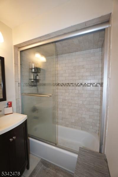 full bath featuring enclosed tub / shower combo and vanity