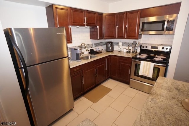 kitchen with light tile patterned floors, stainless steel appliances, a sink, and decorative backsplash