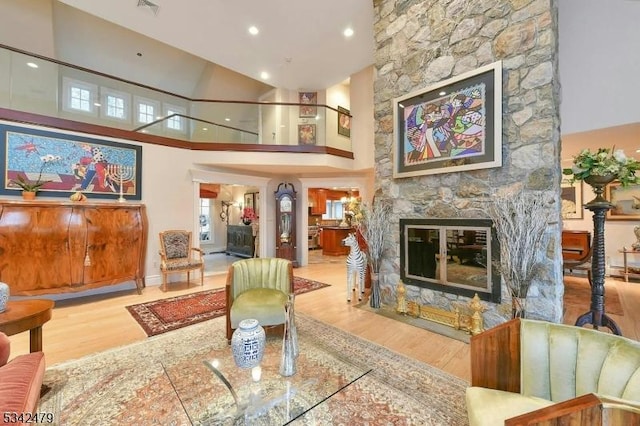 interior space with a high ceiling, a fireplace, wood finished floors, and visible vents