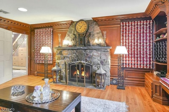 interior space with a baseboard heating unit, a stone fireplace, wood finished floors, and visible vents