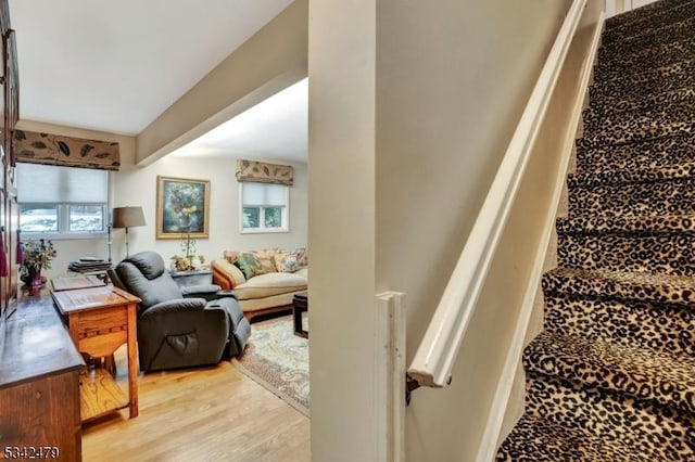 stairway with beamed ceiling, a wealth of natural light, and wood finished floors