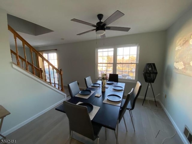 dining room featuring visible vents, stairway, a ceiling fan, wood finished floors, and baseboards